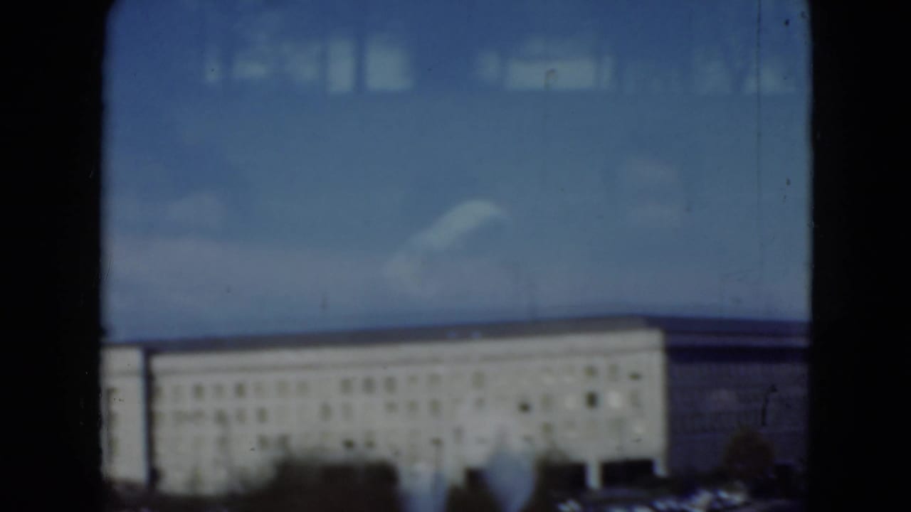 Soft 8mm frame of a large Middletown, Pennsylvania building facade, parking lot, blue sky, and reflected interior shapes on glass.
