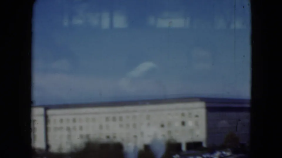 Soft 8mm frame of a large Middletown, Pennsylvania building facade, parking lot, blue sky, and reflected interior shapes on glass.