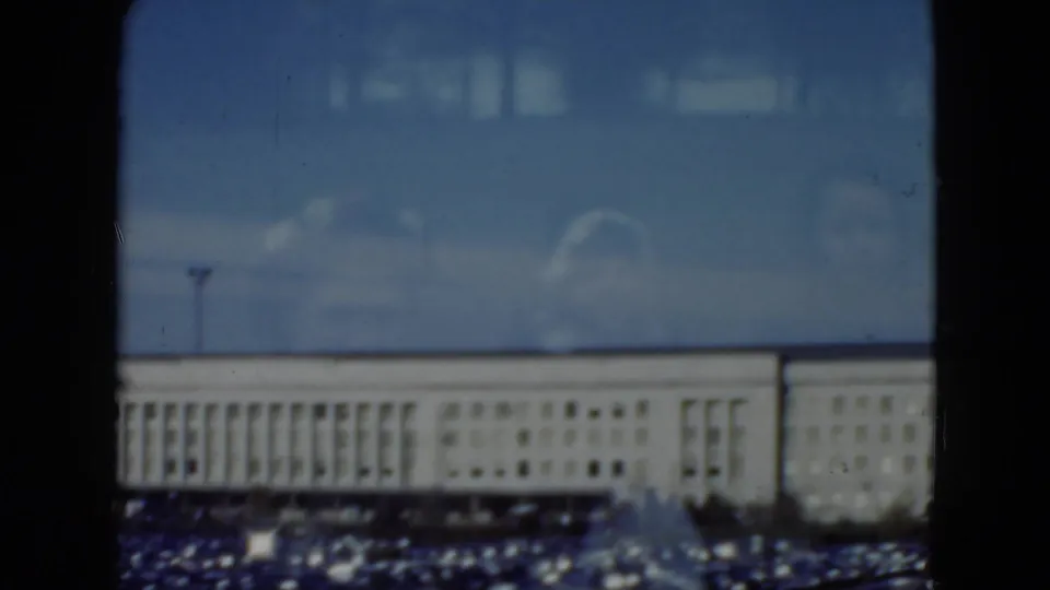 Final 8mm frame of the Middletown exterior, showing the institutional building, foreground parking lot, and interior reflections on glass.