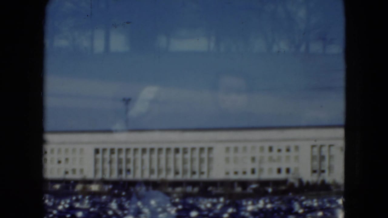 1975 Middletown, Pennsylvania 8mm view of a distant pale institutional building seen through window mullions and reflections.