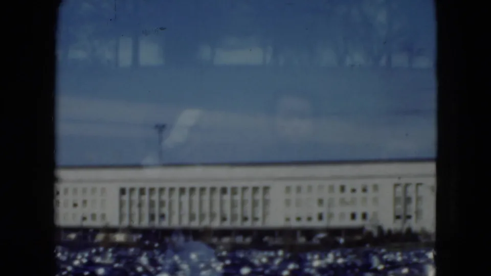 1975 Middletown, Pennsylvania 8mm view of a distant pale institutional building seen through window mullions and reflections.