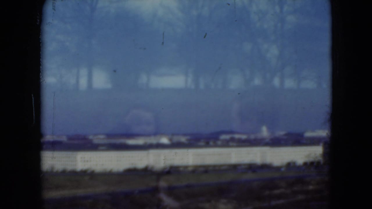 1975 Middletown-area frame with a long pale building, distant rooflines, bare trees, and visible 8mm film wear.