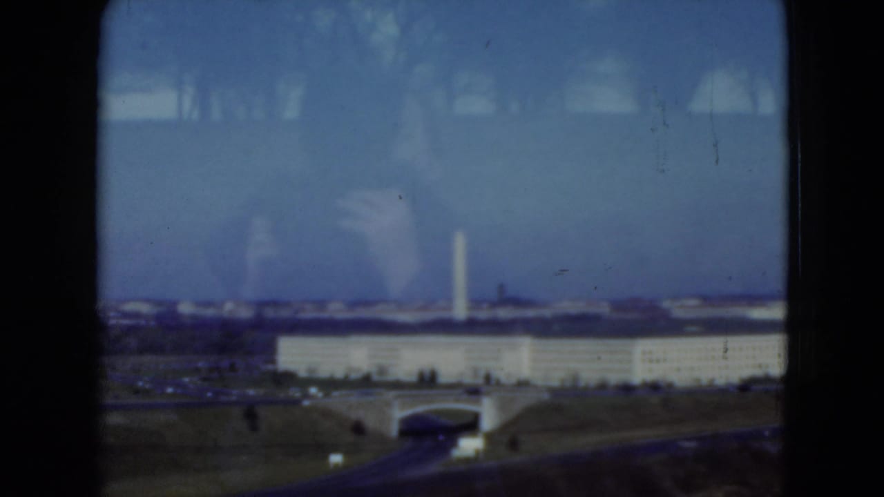 1975 8mm travel frame with the distant Pentagon area and Washington Monument visible beyond open grounds and a roadway.