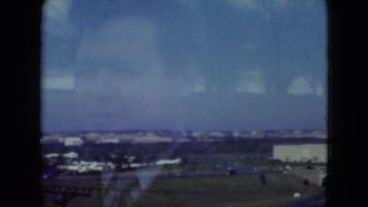1975 Middletown, Pennsylvania home-movie frame showing a hazy elevated suburban landscape with roads, low buildings, and distant trees.
