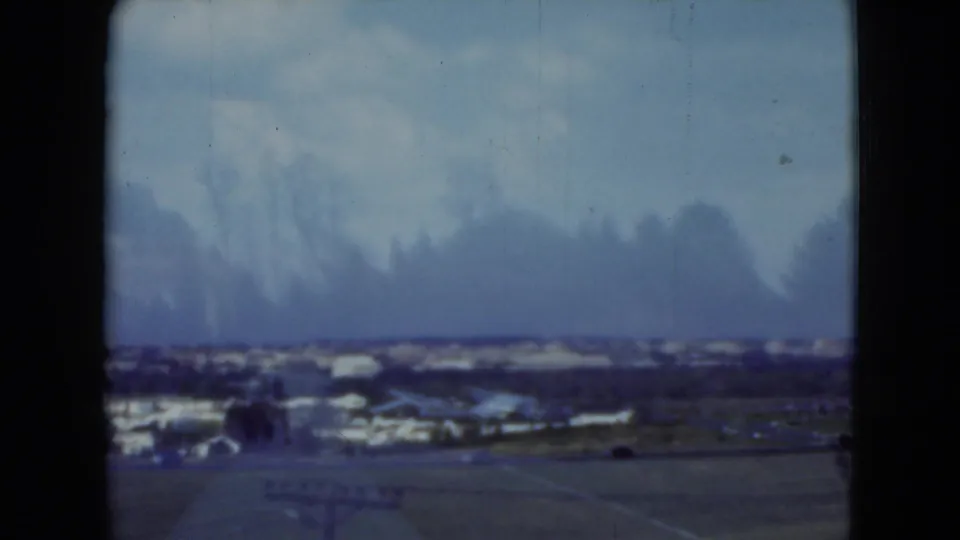 Elevated 1975 Middletown, Pennsylvania view with low buildings, open ground, distant roads, and a hazy blue sky.