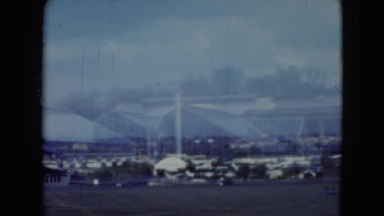 Arched racetrack building with parked cars and foreground frame border.