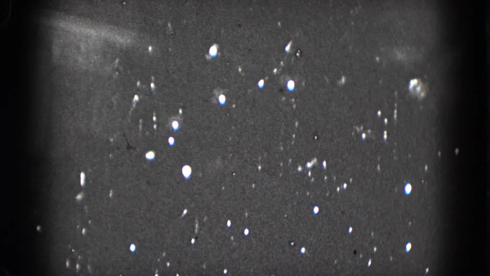 Dim 1975 home-movie frame from Middletown with scattered Christmas tree lights and pronounced physical-film artifacts.