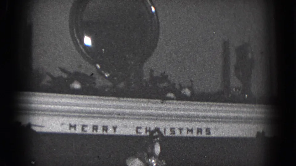 1975 Middletown home-movie frame showing a mantel sign and a large dark glass-like ornament or vessel in a Christmas display.