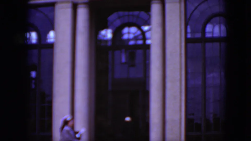Dark 1975 8mm frame from Middletown, Pennsylvania, showing columns and arched windows on a classical exterior with strong blue color shift.