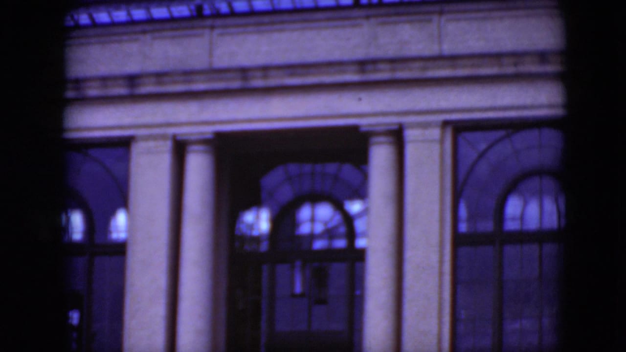 Classical building facade with columns and arched windows seen through dark framing.
