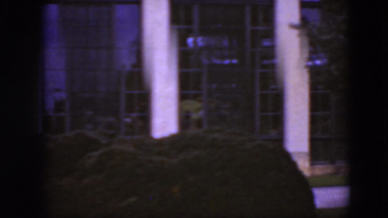 1975 Middletown, Pennsylvania 8mm frame showing tall columns, gridded windows, clipped shrubs, and a partially obstructed exterior view.