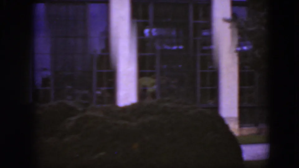 1975 Middletown, Pennsylvania 8mm frame showing tall columns, gridded windows, clipped shrubs, and a partially obstructed exterior view.