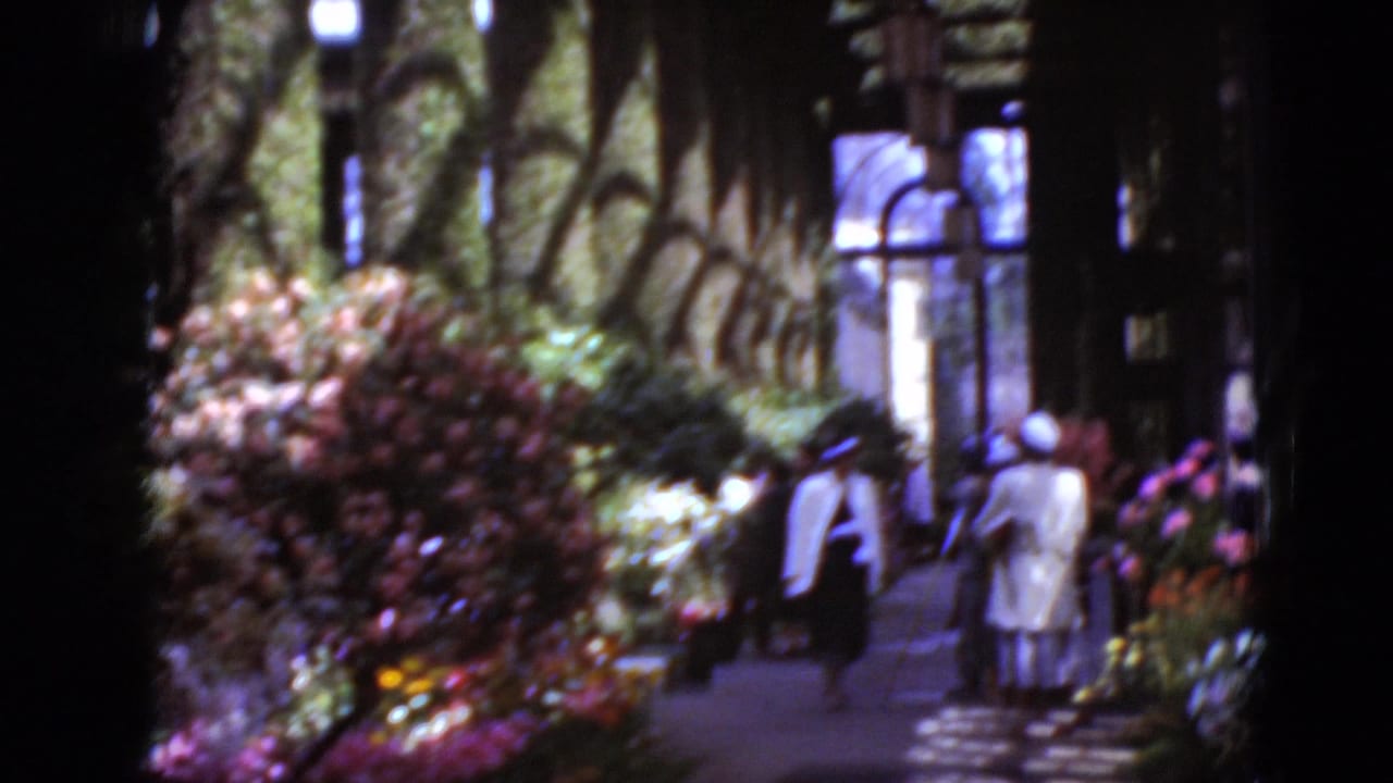 People in light clothing stand near flower beds outside a church building.