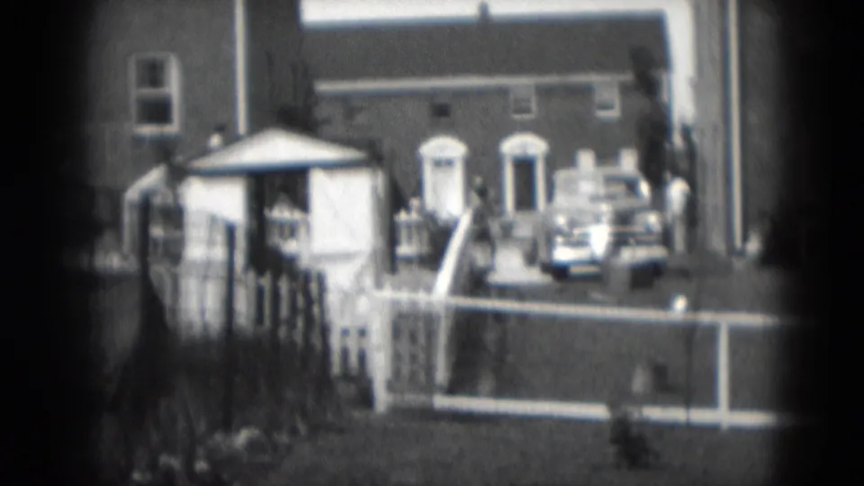 1975 Middletown, Pennsylvania frame with brick homes, white fencing, steps, a small yard structure, and an older car parked outside.