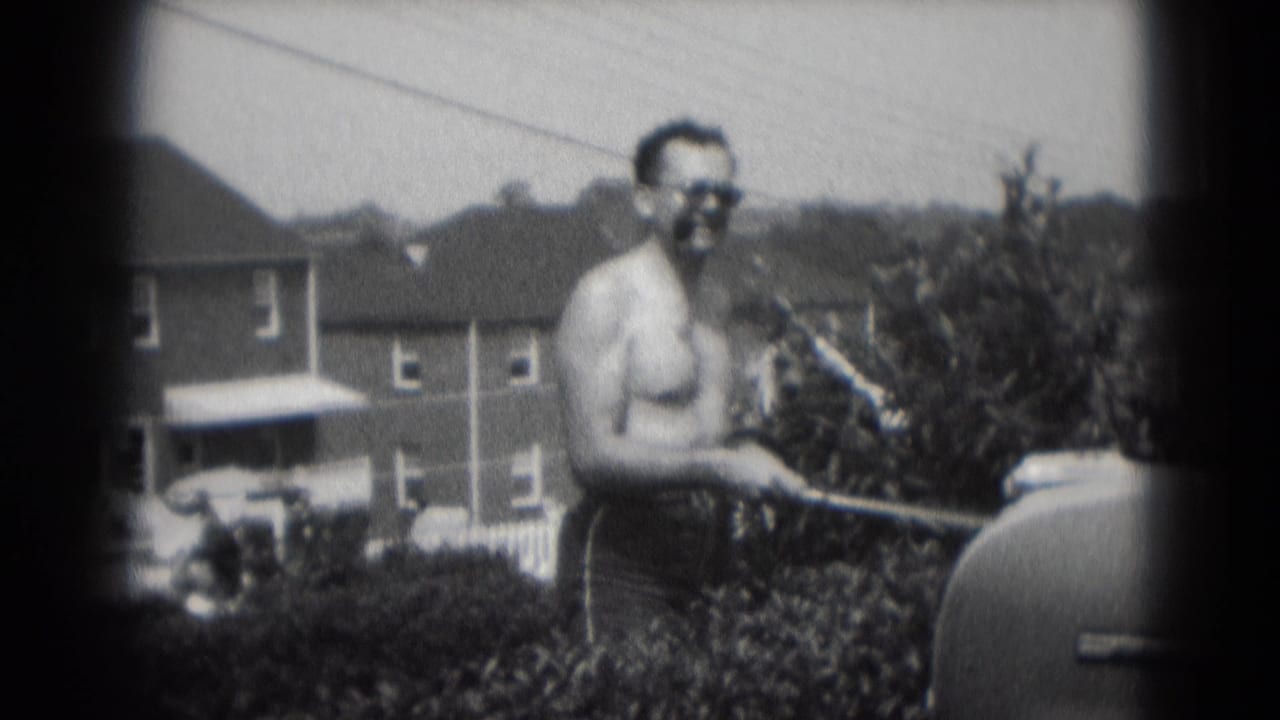 Man with sunglasses and cigar stands beside a backyard grill.