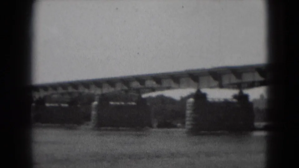 A slow pan reveals more of the bridge structure, including a prominent stone pier and the riverbank beyond.