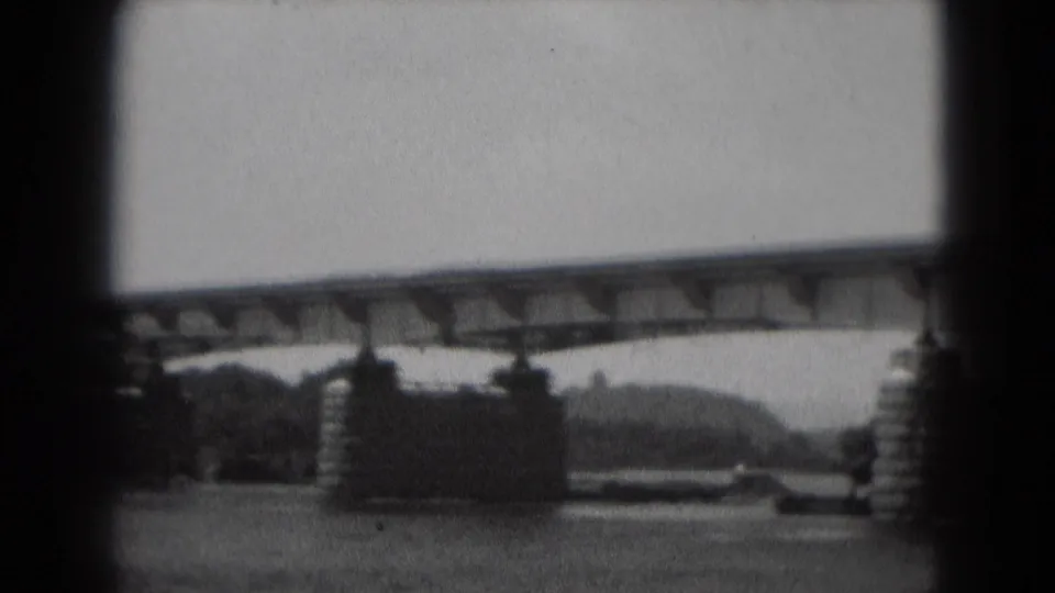 The final frame shows the bridge stretching over the river, with stone piers, shoreline, and grainy 8mm edges visible.