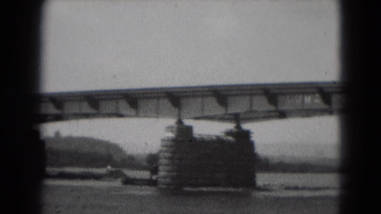 Bridge deck crosses the frame above river water and large supports.