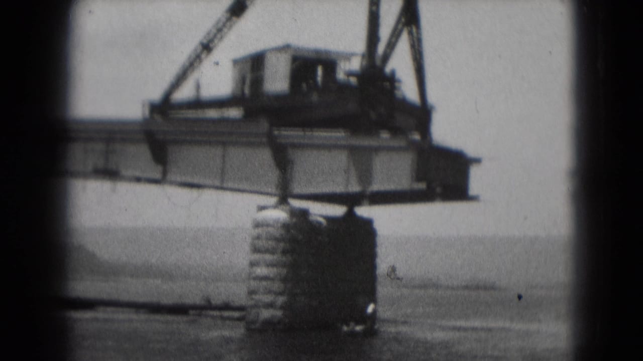 1975 Middletown, Pennsylvania 8mm frame showing a crane and large steel beam above water on a cylindrical support.