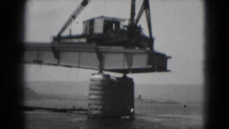 1975 Middletown, Pennsylvania 8mm frame showing a crane and large steel beam above water on a cylindrical support.