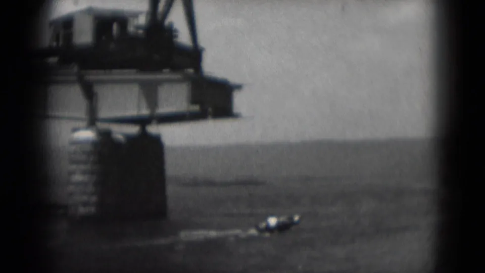 A small boat passes beneath the construction area while the crane and steel beam dominate the 1975 8mm frame.