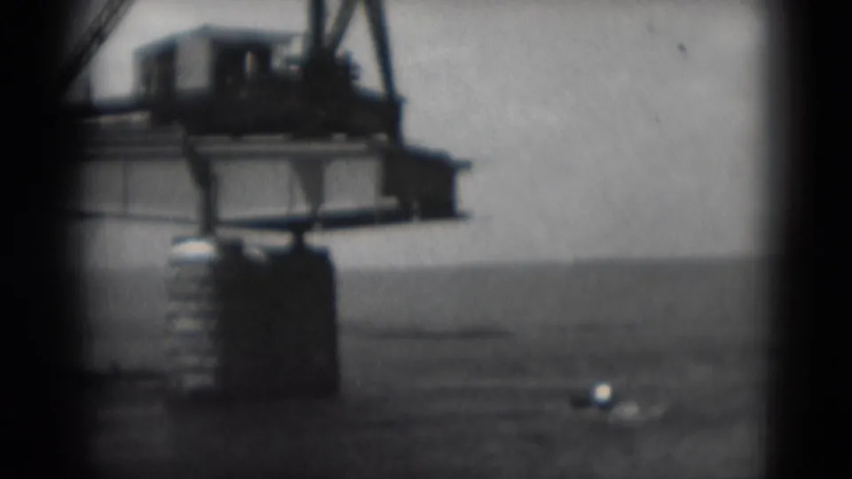 Middletown, Pennsylvania waterfront crane seen in soft black-and-white 8mm footage, with a small boat moving across the river.