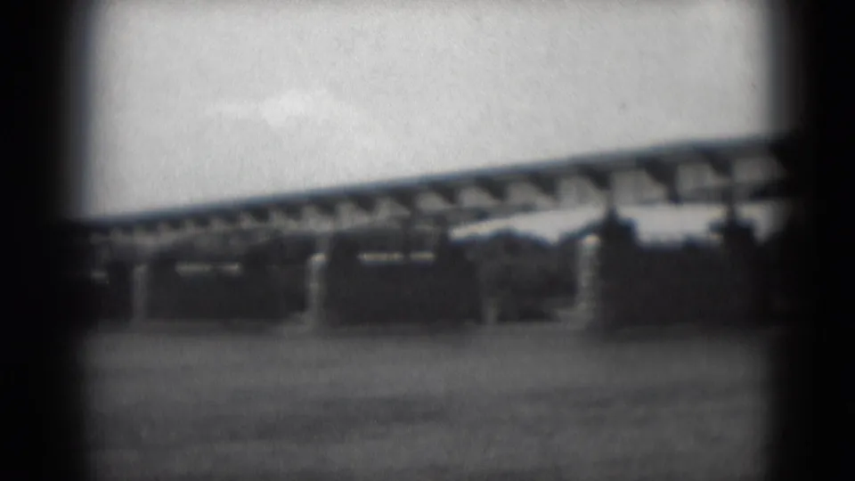 A soft 8mm frame shows the Middletown bridge crossing water, partly obscured by dark film-edge framing and distant trees.