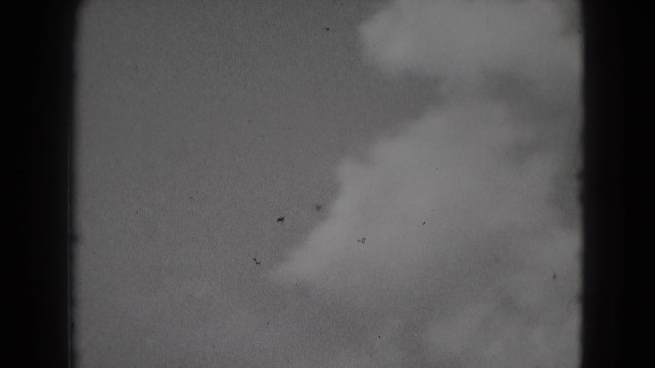 1975 Middletown, Pennsylvania 8mm frame showing a cloudy pale sky, soft focus, dark edge borders, grain, and small dust specks.