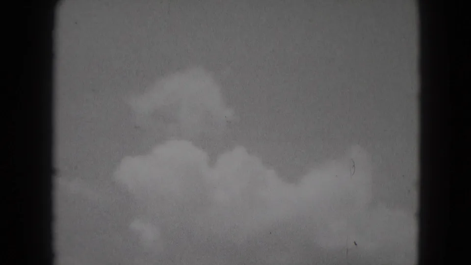 1975 Middletown, Pennsylvania 8mm frame showing brighter cloud shapes low in the sky, with visible grain, dust, and dark film borders.
