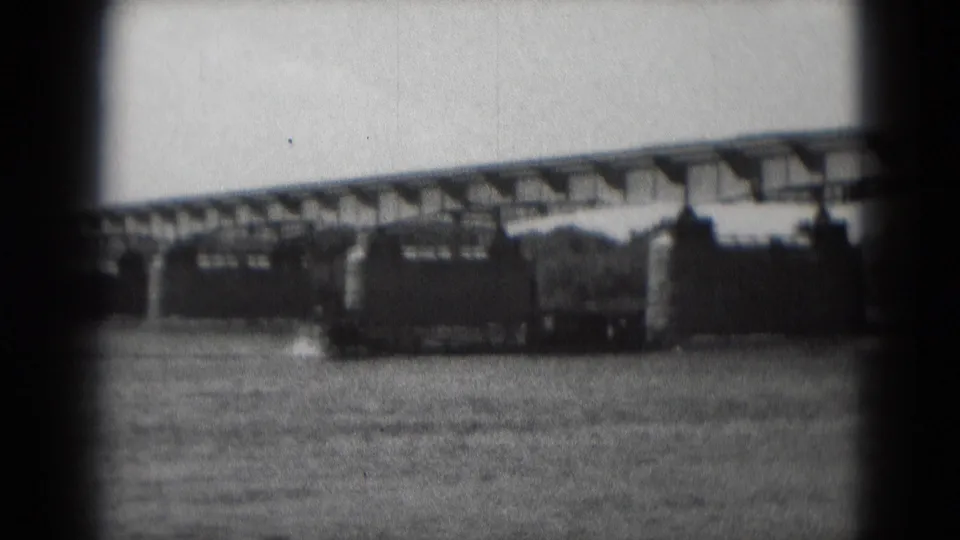 Final frame shows the dark vessel on the river below the bridge, with shoreline trees and 8mm gate edges visible.