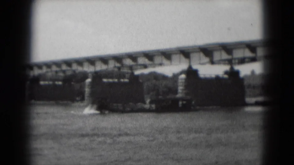 Soft black-and-white 8mm frame of a sternwheeler-style boat on the river beneath a bridge in Middletown, Pennsylvania.