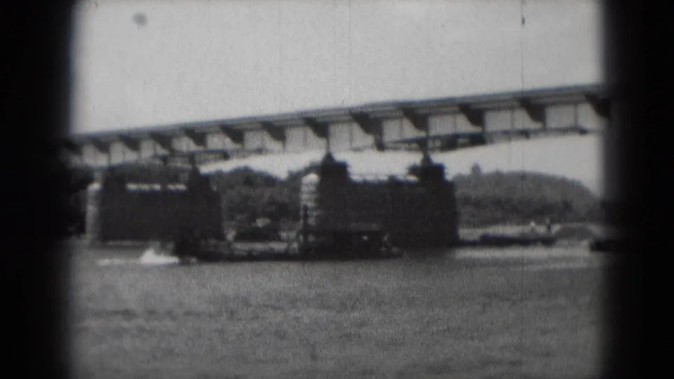 1975 Middletown, Pennsylvania home-movie frame showing bridge construction over water with piers, steel work, and crane activity.