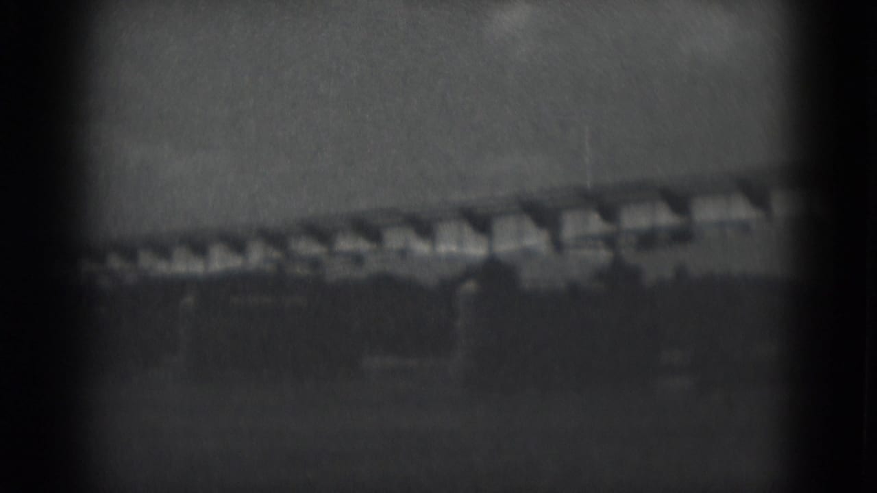 Soft distant view of a long elevated structure over open land.