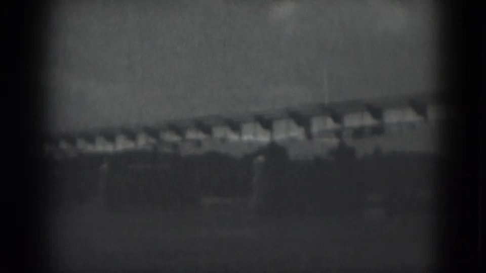Grainy 1975 Middletown, Pennsylvania home-movie view of a long elevated structure across a rural horizon.