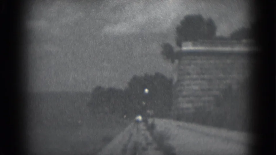 1975 8mm home-movie frame from Middletown, Pennsylvania, looking along a dock or path beside dark water and an overcast horizon.