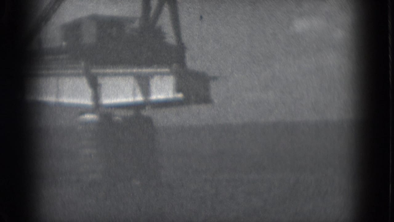 1975 Middletown, Pennsylvania 8mm frame showing a crane boom over a suspended bridge section in soft black-and-white focus.
