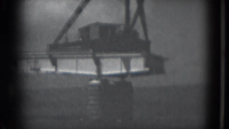 Black-and-white 8mm view of a crane lifting a bridge section in Middletown, Pennsylvania, with the scene partly obscured by grain and vignetting.