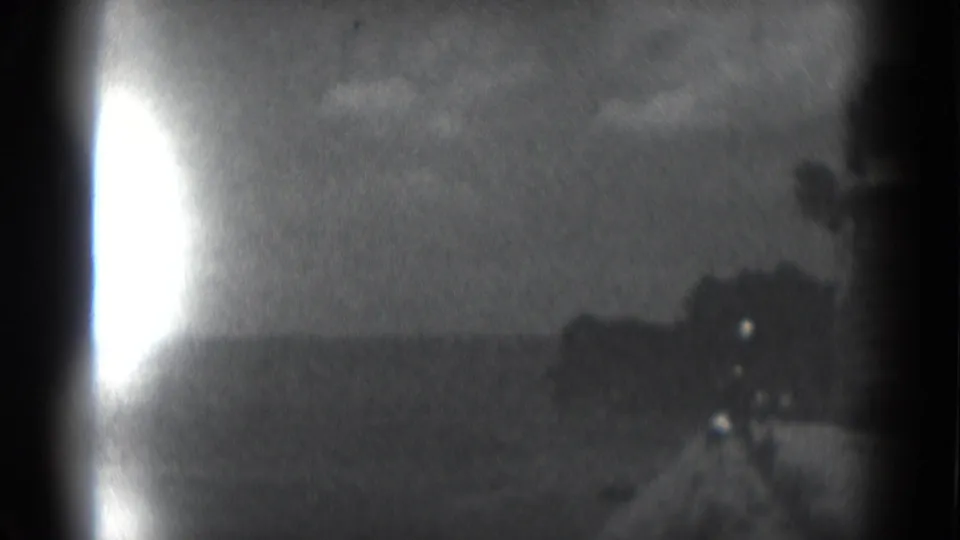 Final 8mm frame from the Middletown construction scene, showing a dark structure at right and a bright exposure flare at the left edge.