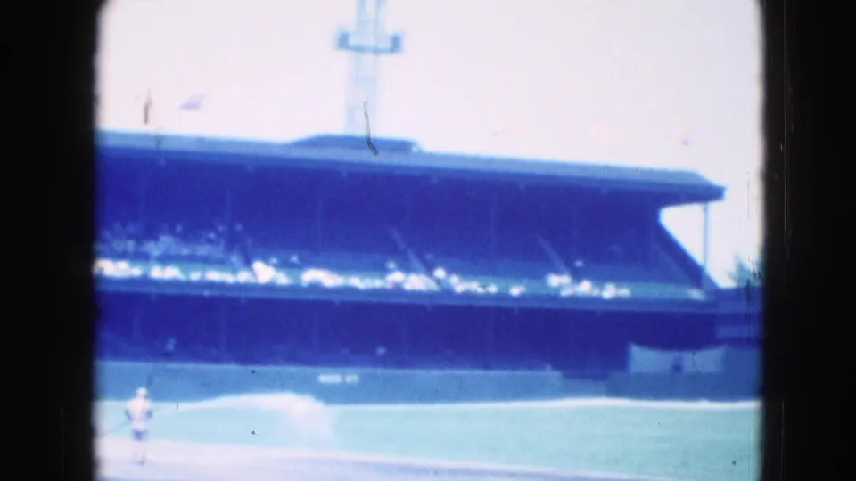 Later frame from the 1975 Middletown baseball clip showing a distant field crew or players below the crowded grandstand.