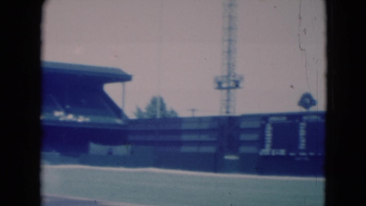 Outfield wall and scoreboard near a covered baseball grandstand.