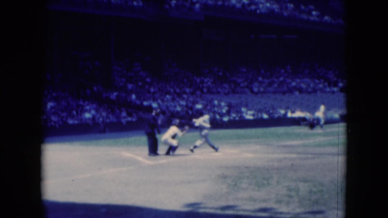 Batter follows through after contact near home plate as the catcher crouches.