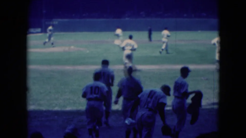 1975 8mm baseball scene in Middletown with players near the sideline in the foreground and other players spread across the field.