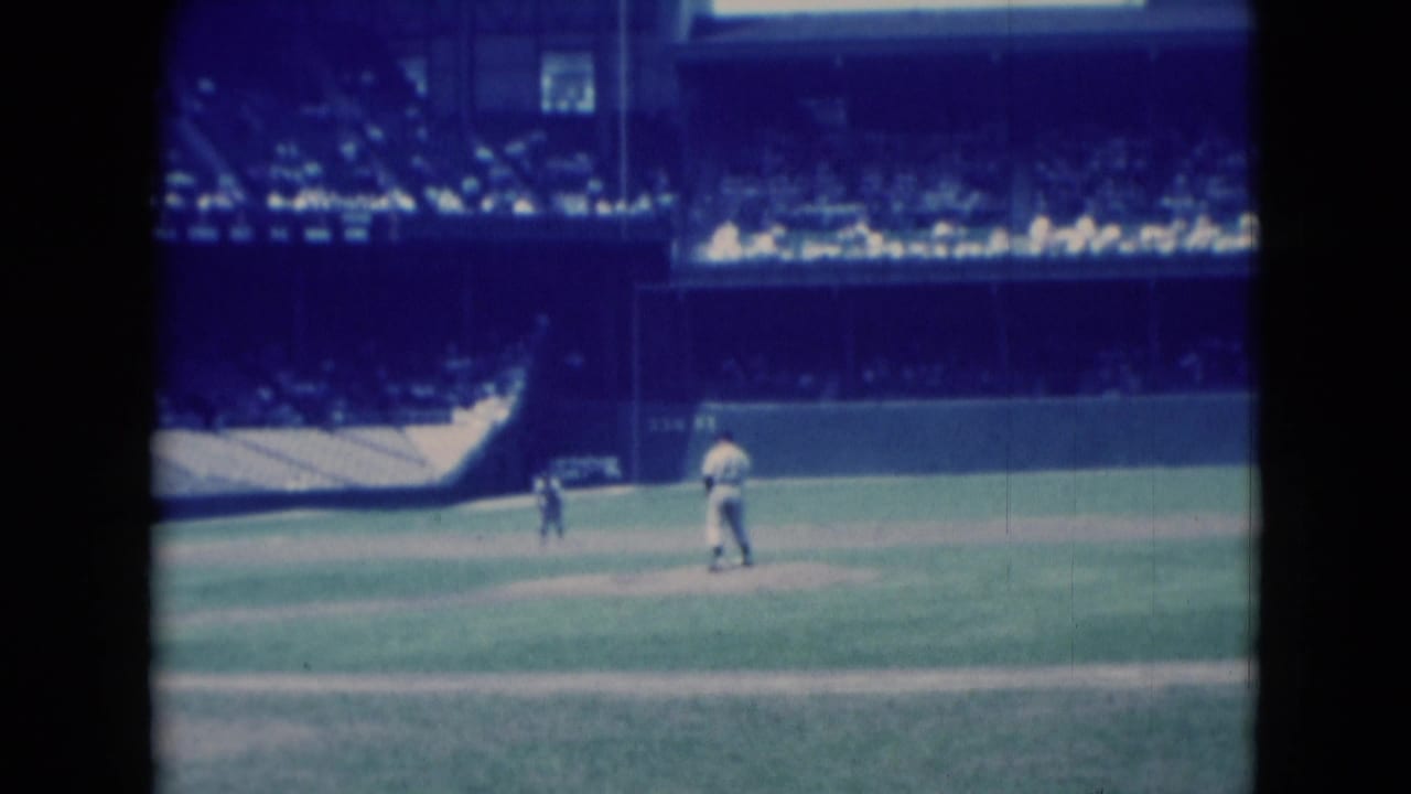 Wide 8mm view of a local baseball game in Middletown, Pennsylvania, with players near the infield and crowd seating beyond.