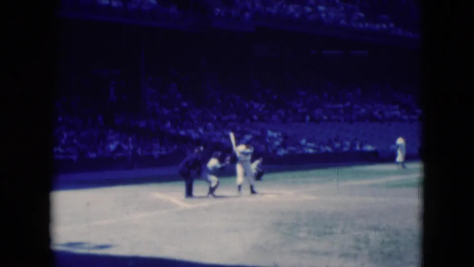 1975 Middletown, Pennsylvania baseball frame showing a batter at home plate with nearby game officials or players and a crowded stand behind.
