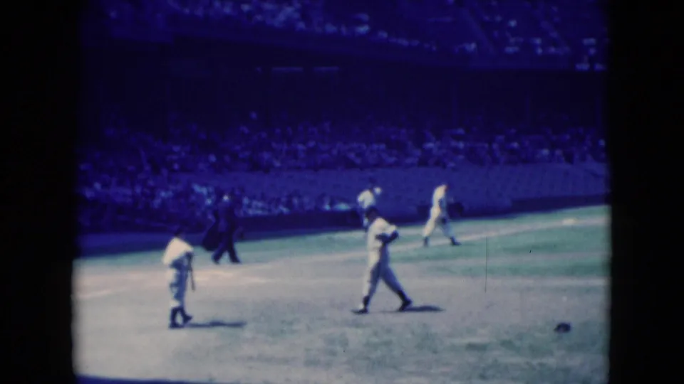 1975 Middletown, Pennsylvania 8mm frame showing players and a dark-clad official crossing the field before a packed stadium section.