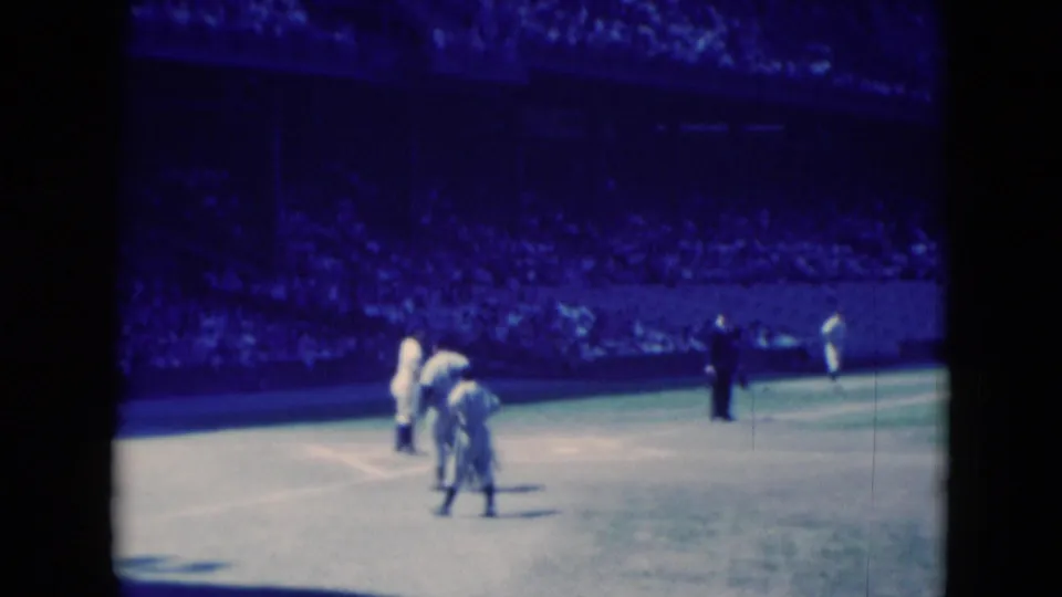 1975 Middletown, Pennsylvania 8mm still showing players near the cricket pitch area, with spectators filling the stands in the background.