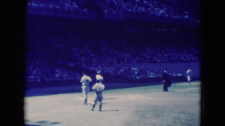 1975 Middletown, Pennsylvania frame of players moving across an outdoor cricket ground, seen from a distant spectator position.