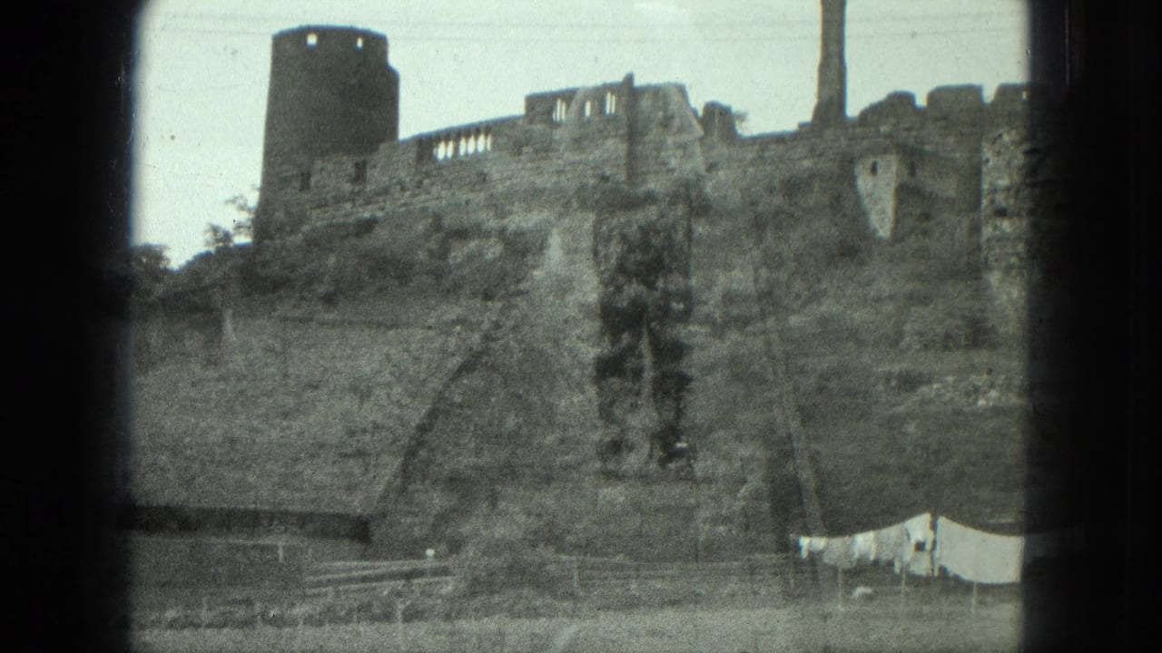 Weathered stone ruin on a hillside with a round tower and laundry line below.