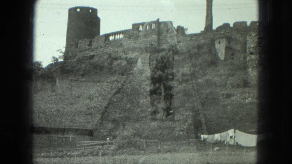 1975 8mm frame listed as Milwaukee, showing a hillside stone ruin, round tower, chimney, trees, and laundry hanging below.