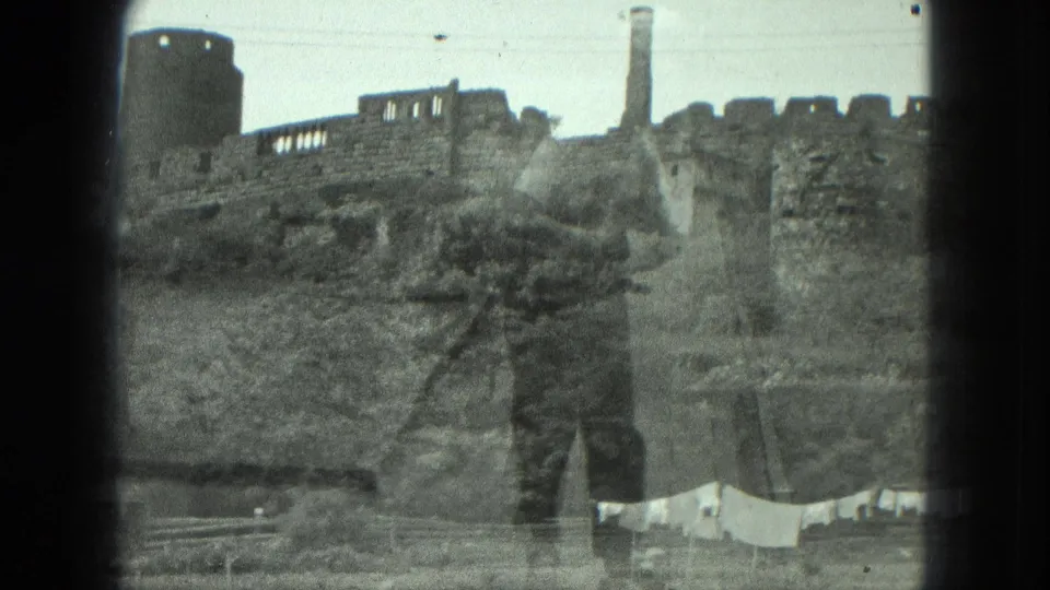 The listed Milwaukee 1975 frame holds on ruined masonry, a cylindrical tower, a chimney, hillside brush, and laundry in the lower foreground.